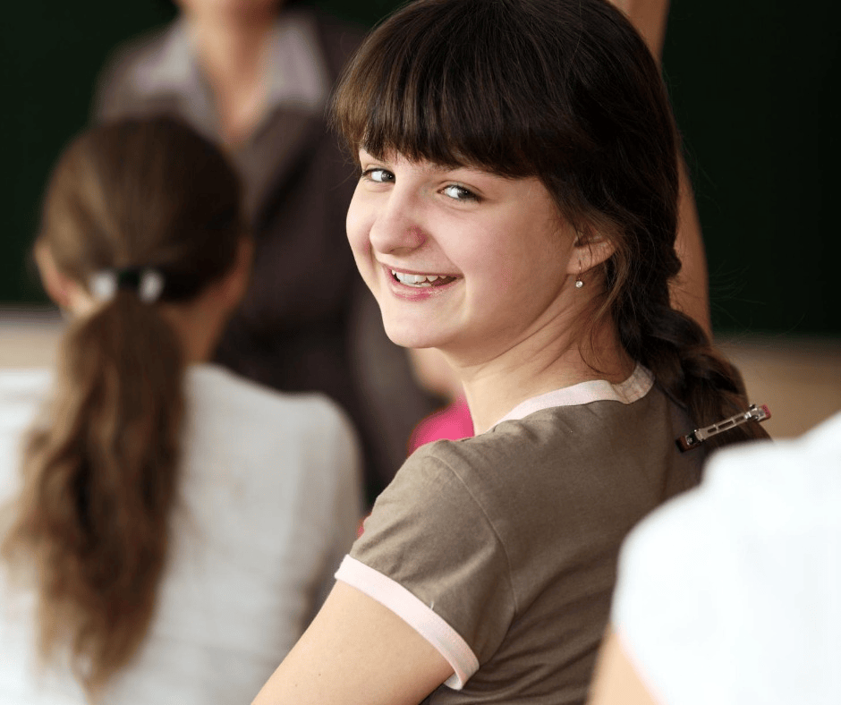Wijkunnenmeer-meisje-lachend-klaslokaal Wijkunnenmeer - Meisje dat lachend achterom kijkt in klaslokaal, symbool voor sprankelend kind.